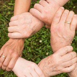 Five hands together in a circle holding each other's wrists