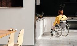 Open plan dinning room and white kitchen with a woman in a wheelchair