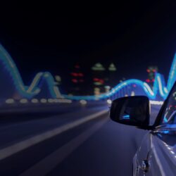 Side of a car driving at night with lights reflected on it